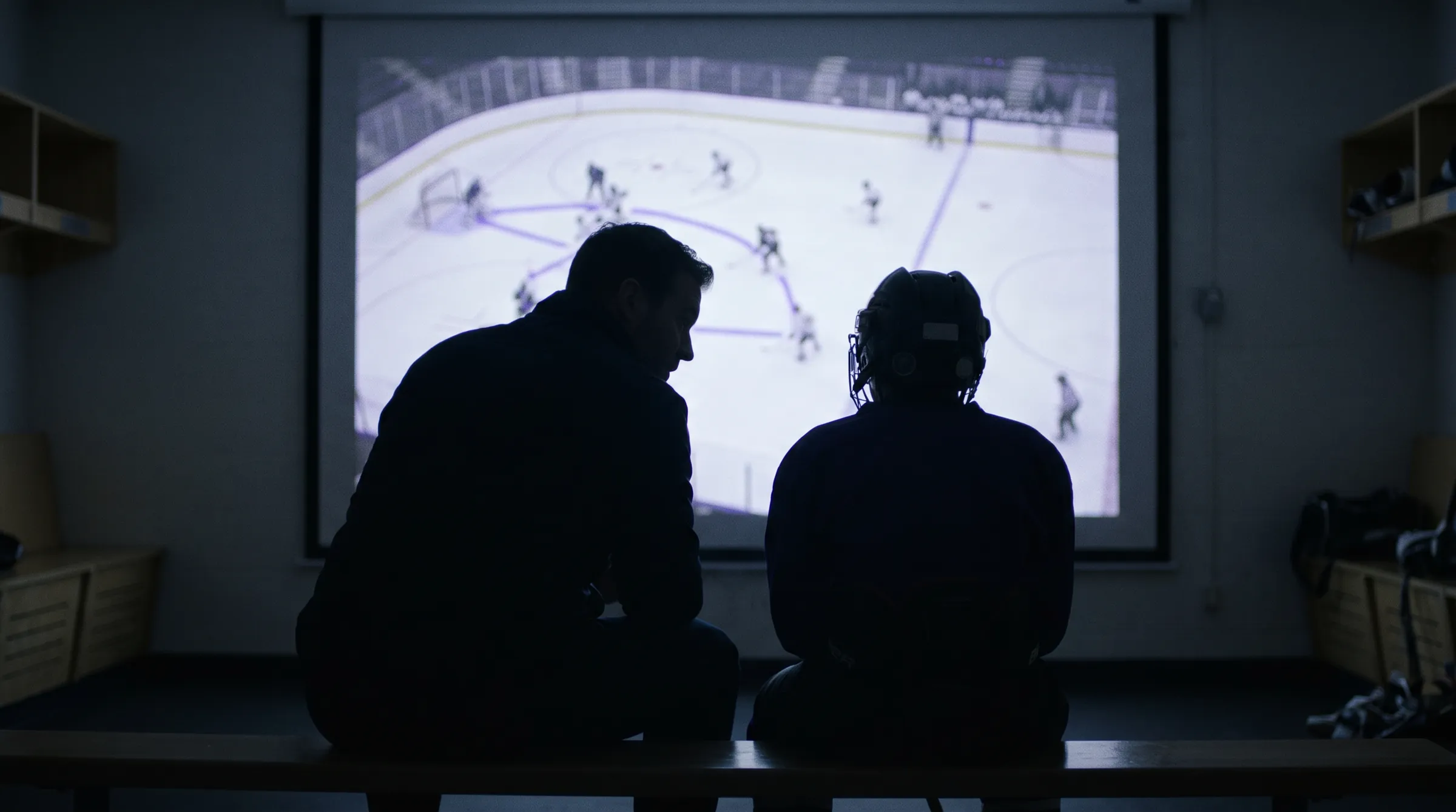 Coach and player reviewing game film on a large screen