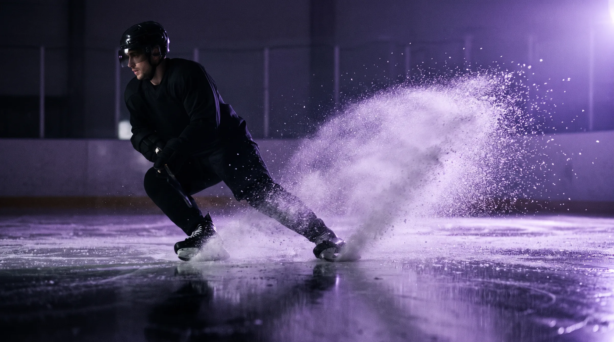 Player in black gear throwing up a spray of ice on a hard stop